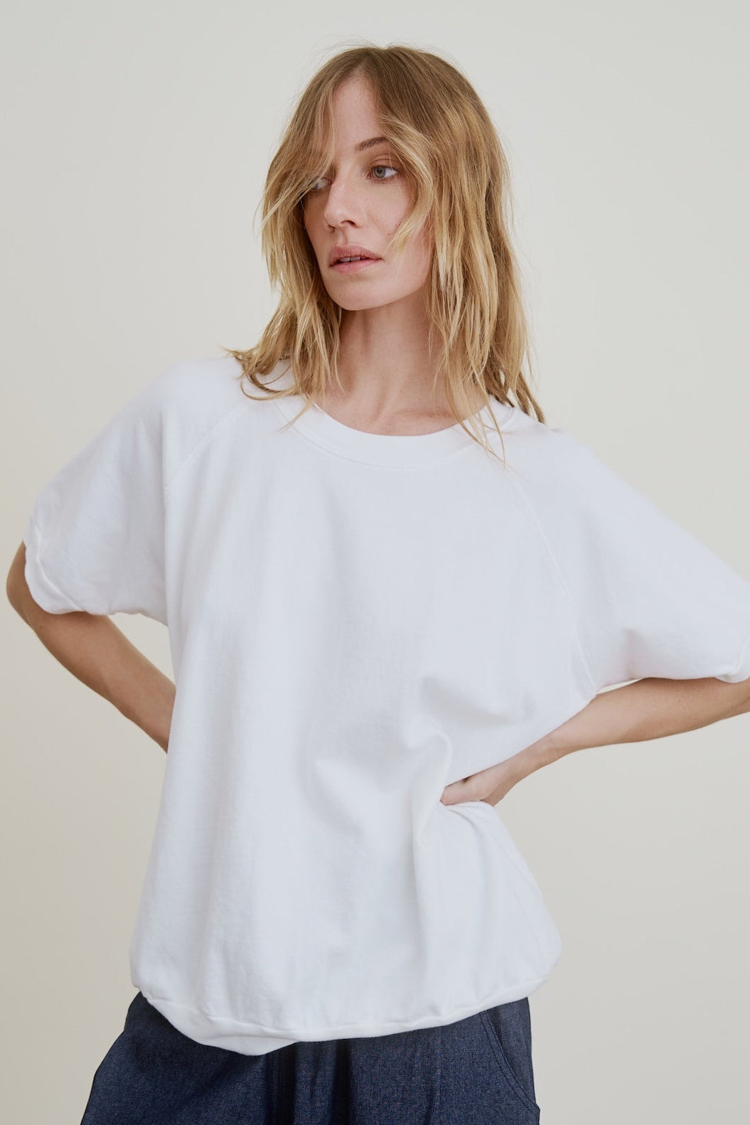 Woman wearing a white oversized t-shirt against a plain background